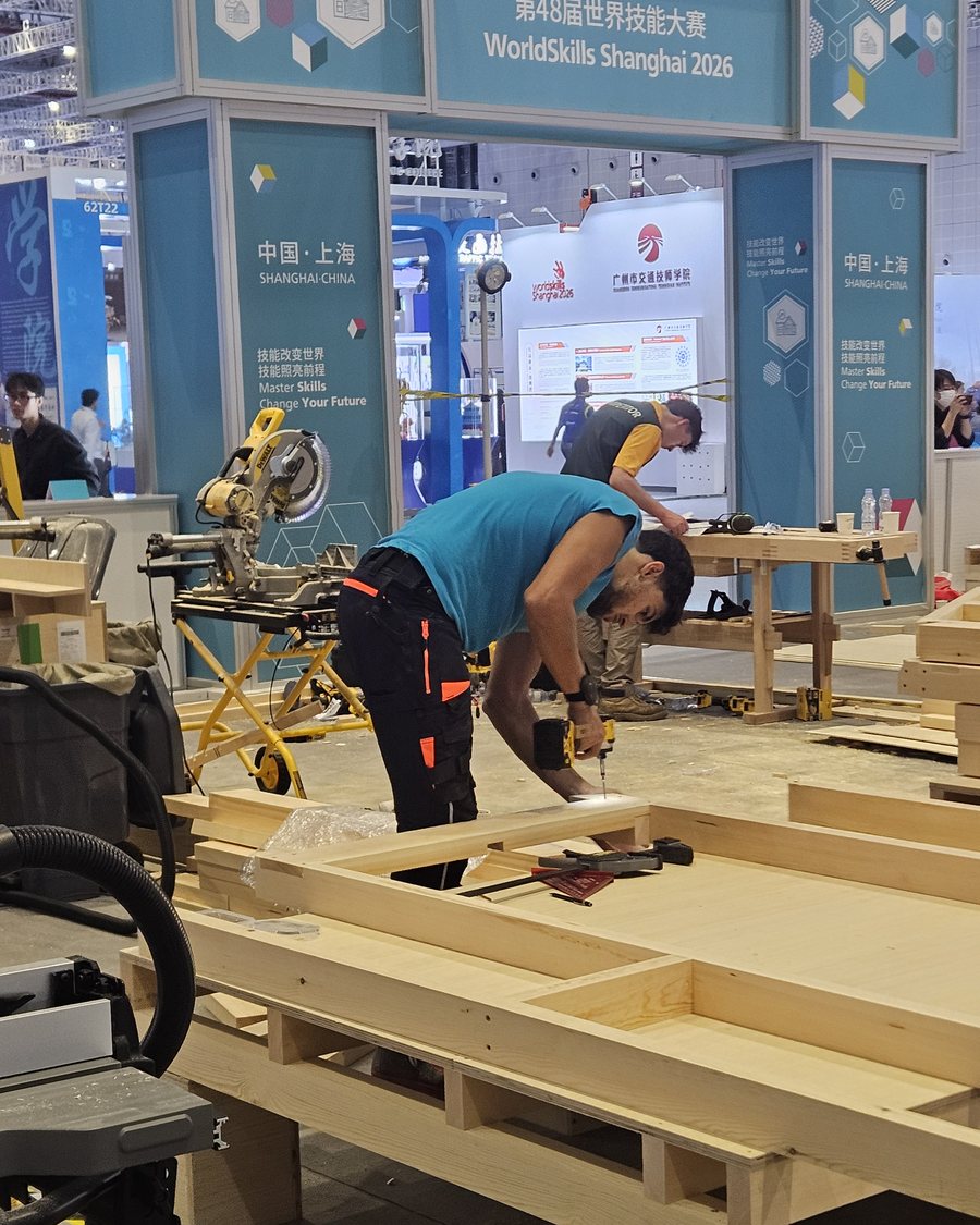 Un compétiteur visse une ossature sous le portique WorldSkills Shanghai 2026